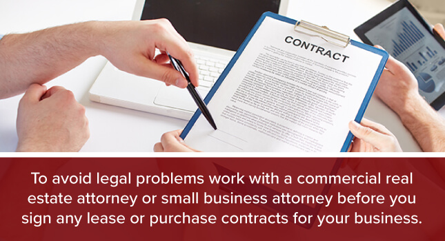 A person points a pen at the signature line of a contract 